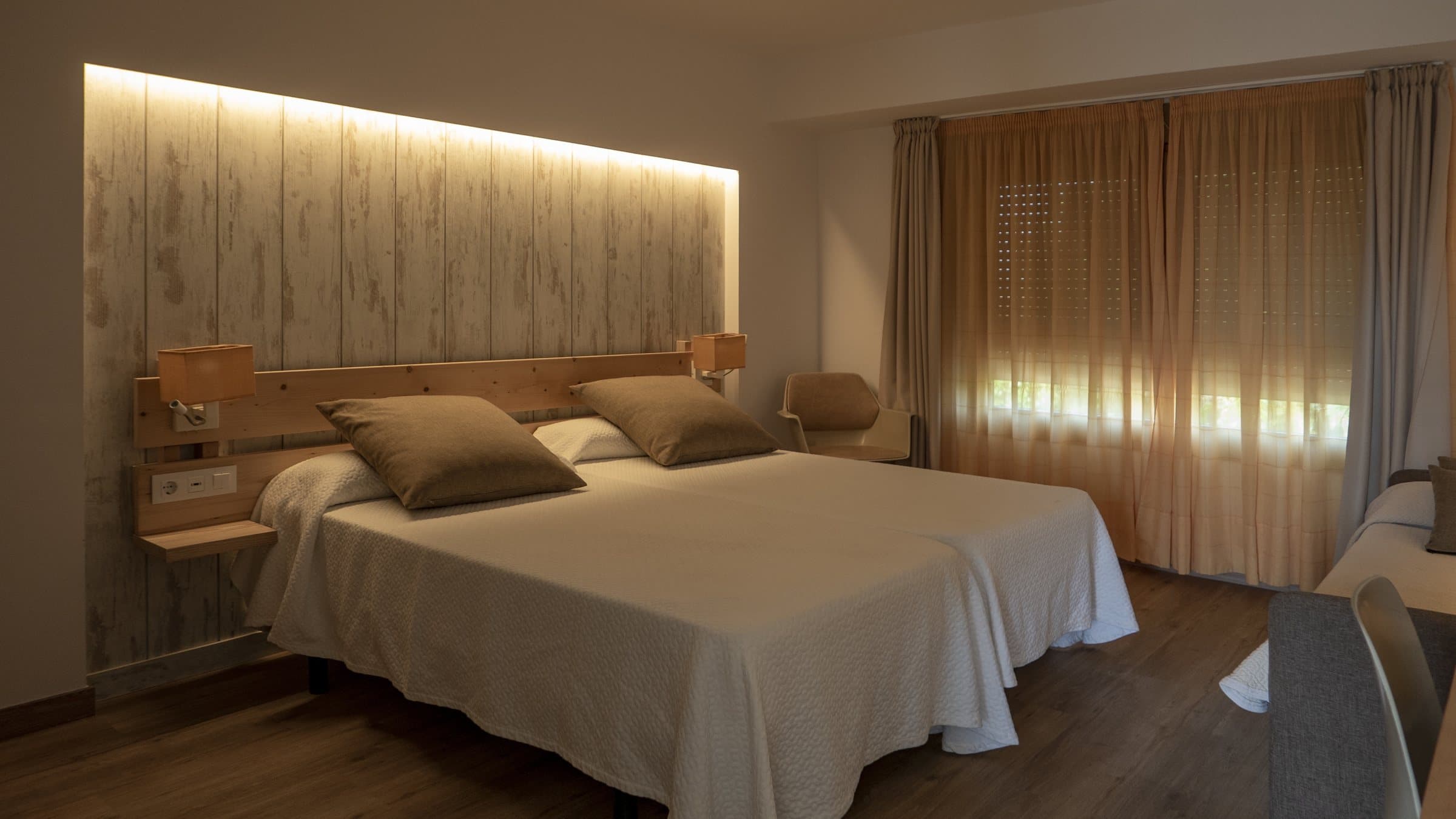 Hotel room in warm cream tones with crisp white bedding