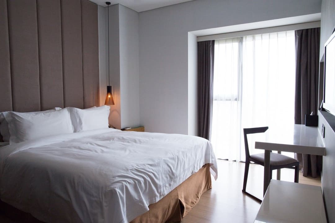 Bright guest bedroom with a made double bed and a desk