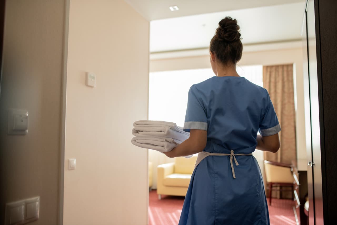 Housekeeper carrying clean white towels into a hotel room