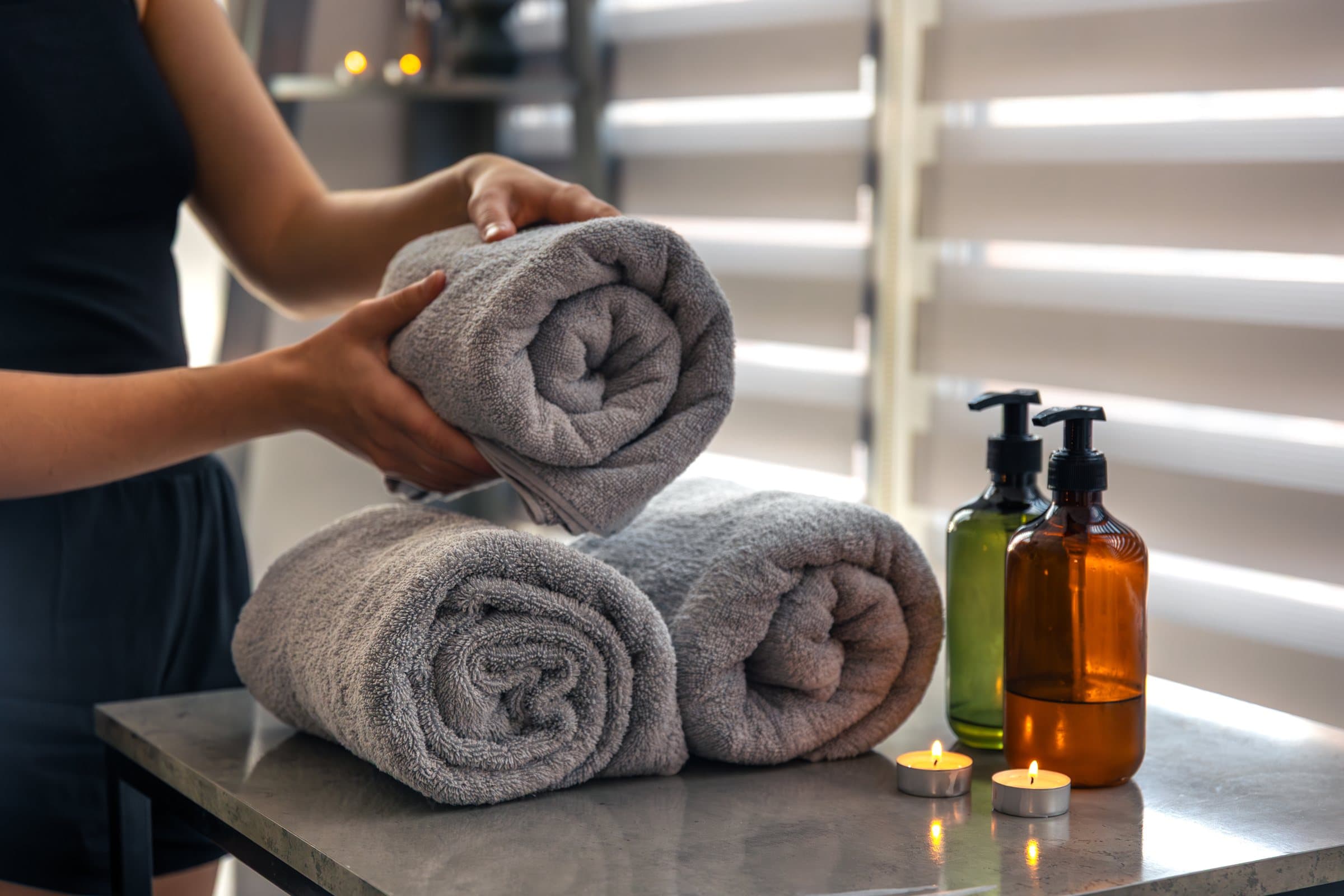 Spa attendant setting out rolled grey towels