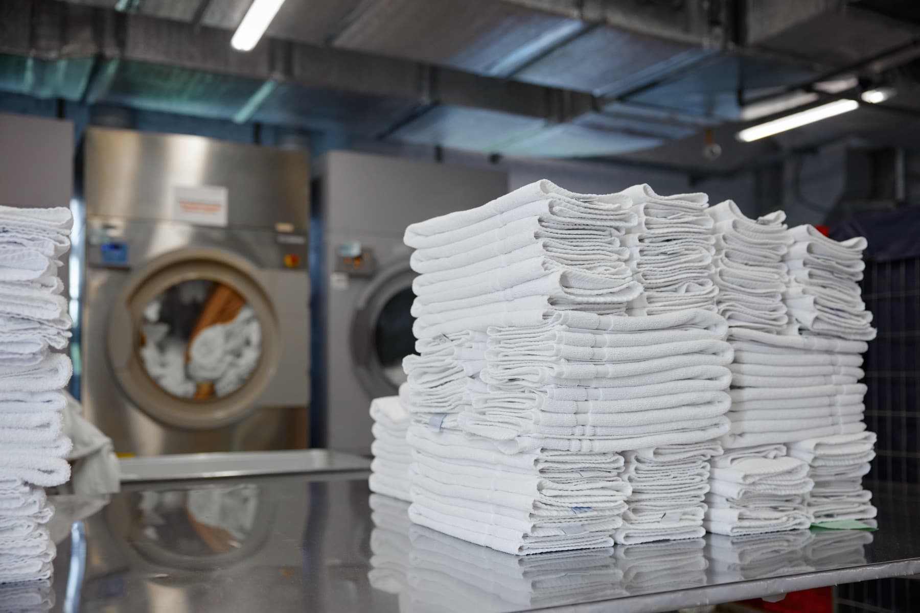 Stacks of folded white towels in a commercial laundry