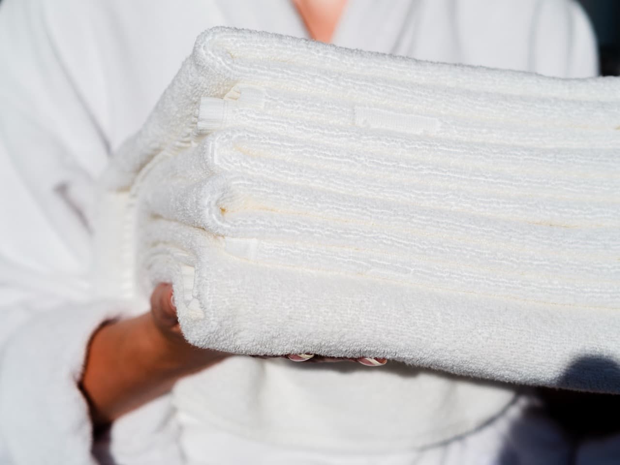 Stack of folded white towels held in two hands