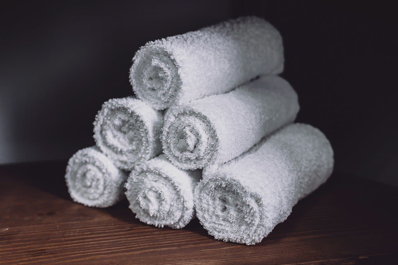 Rolled white towels stacked on a dark wooden surface